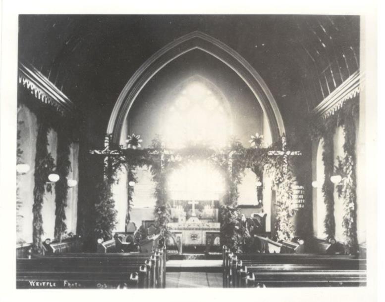 Historic photo of church internior decorated with evergreen for Christmas.
