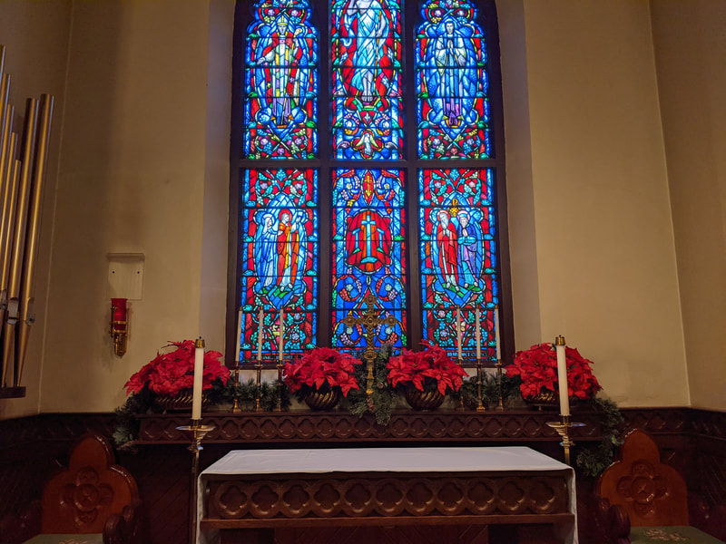 Altar of the Episcopal Church of the Good Shepherd with stained glass window and poinsettias.